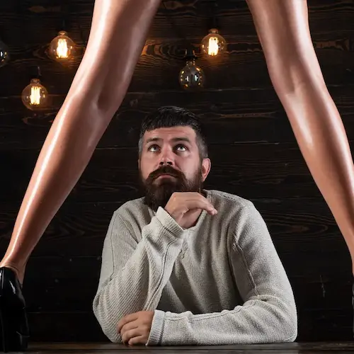 Man looking playfully between woman's legs as she laughs