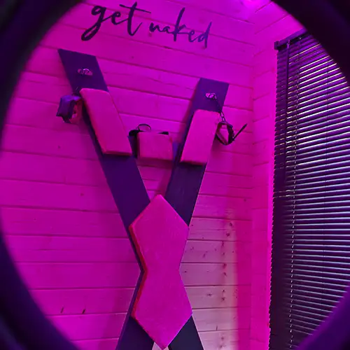 St. Andrew’s Cross in a private playroom, lit with purple glow